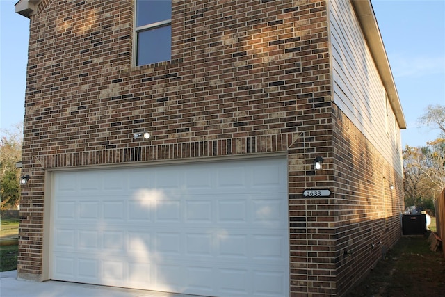 view of side of home featuring a garage and brick siding