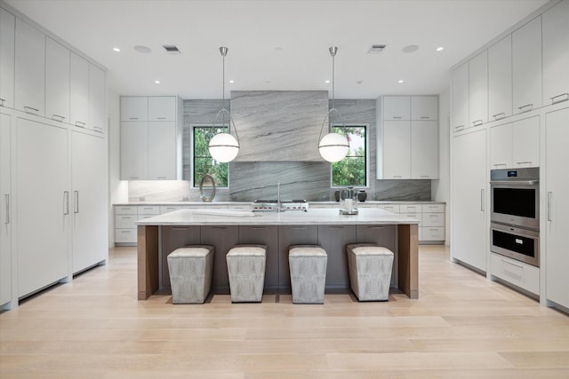 kitchen with light wood-style flooring, light countertops, and backsplash