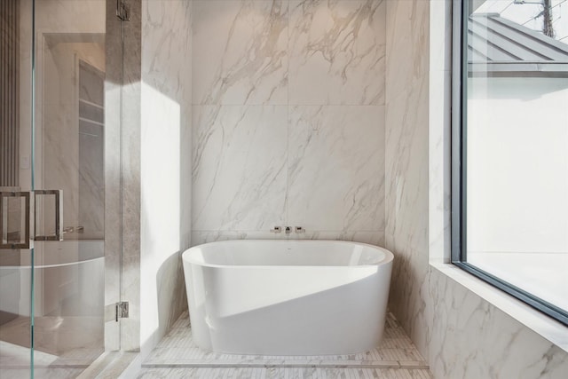 full bath with a freestanding tub, a shower stall, and tile walls