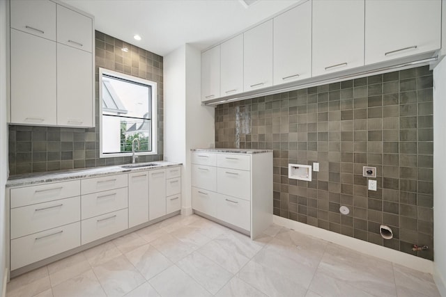 interior space featuring light tile patterned floors, hookup for a washing machine, recessed lighting, a sink, and cabinet space