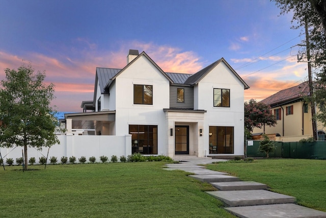 modern inspired farmhouse featuring a standing seam roof, fence, metal roof, and a yard