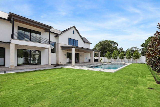 rear view of house with a patio, stucco siding, a lawn, a balcony, and a fenced backyard