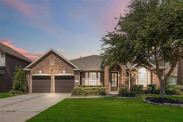 view of front of property featuring brick siding, a yard, a shingled roof, concrete driveway, and a garage