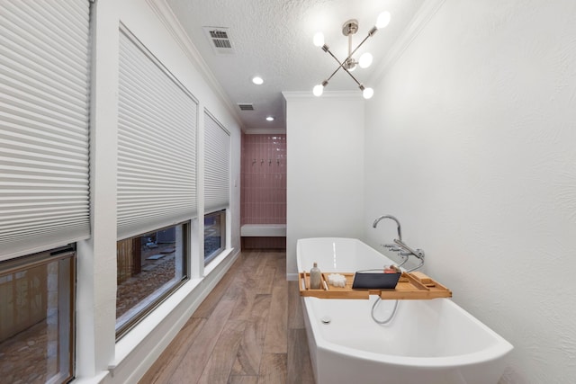 53 La Costa Dr, Montgomery, TX 77356 - bathroom with visible vents, ornamental molding, wood finished floors, a freestanding bath, and a textured ceiling
