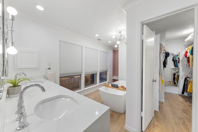 53 La Costa Dr, Montgomery, TX 77356 - bathroom featuring a sink, wood finished floors, a spacious closet, ornamental molding, and a soaking tub