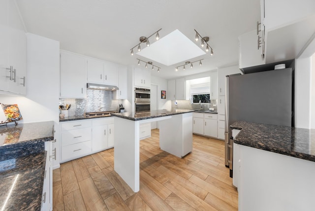 53 La Costa Dr, Montgomery, TX 77356 - kitchen with light wood-type flooring, under cabinet range hood, white cabinetry, and decorative backsplash