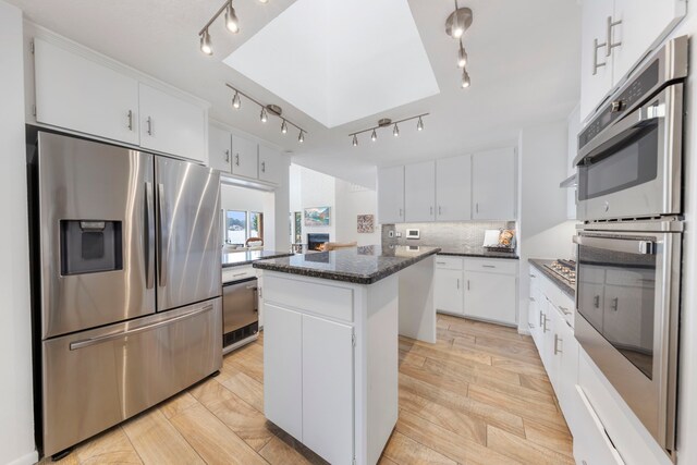 53 La Costa Dr, Montgomery, TX 77356 - kitchen with a center island, white cabinetry, appliances with stainless steel finishes, wood tiled floor, and tasteful backsplash
