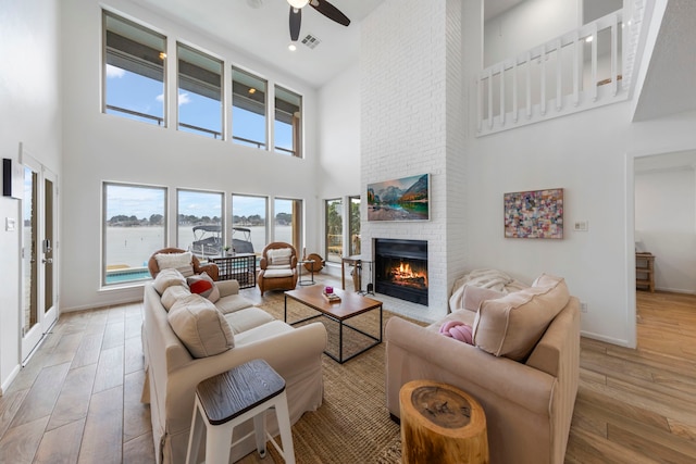 53 La Costa Dr, Montgomery, TX 77356 - living area featuring visible vents, light wood-style flooring, a ceiling fan, a brick fireplace, and baseboards