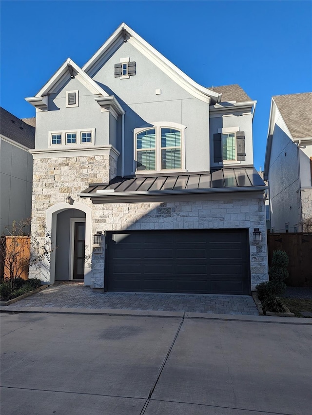 view of front of house featuring decorative driveway, stucco siding, an attached garage, a standing seam roof, and metal roof