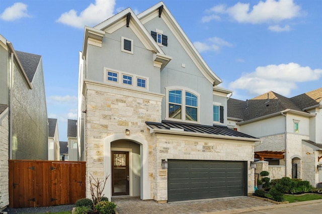 view of front of house with stone siding, metal roof, an attached garage, a standing seam roof, and decorative driveway