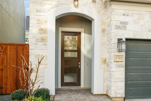 entrance to property with stone siding and fence