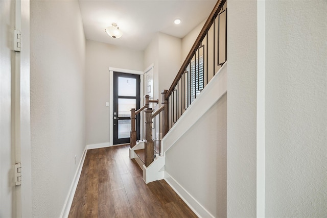 entrance foyer featuring dark wood-type flooring, baseboards, and stairs