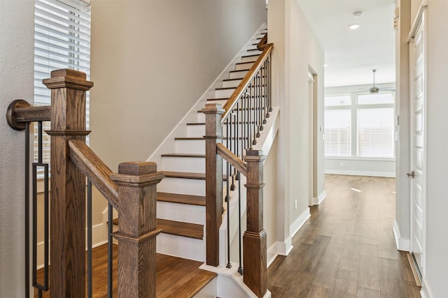 staircase featuring ceiling fan, baseboards, and wood finished floors