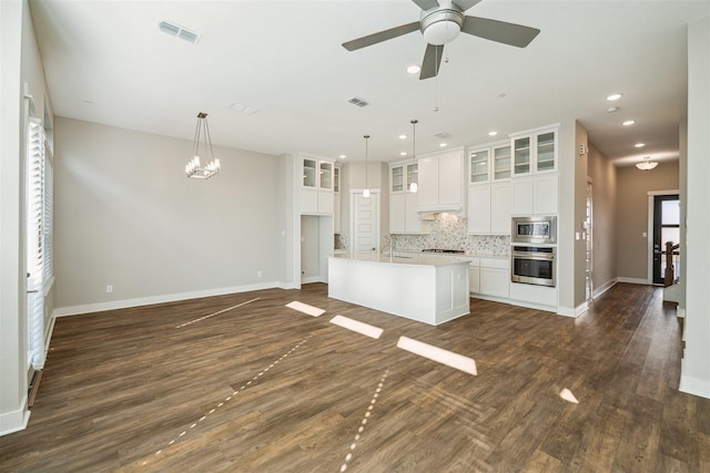 kitchen featuring visible vents, dark wood-style floors, glass insert cabinets, stainless steel appliances, and backsplash