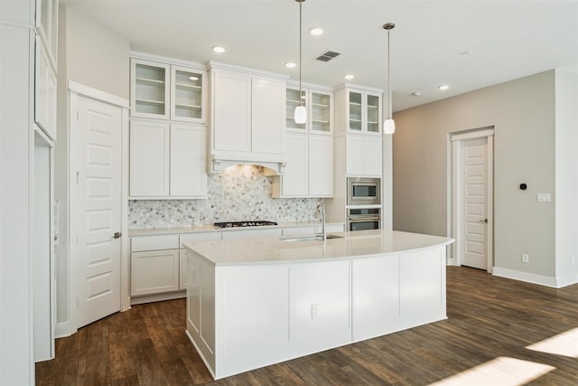 kitchen featuring stainless steel appliances, light countertops, visible vents, dark wood-type flooring, and a sink