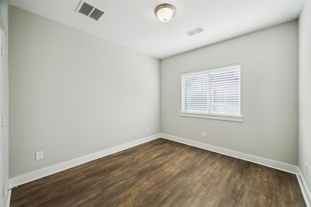 unfurnished room featuring baseboards, visible vents, and dark wood-type flooring