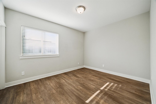 empty room with baseboards and dark wood finished floors