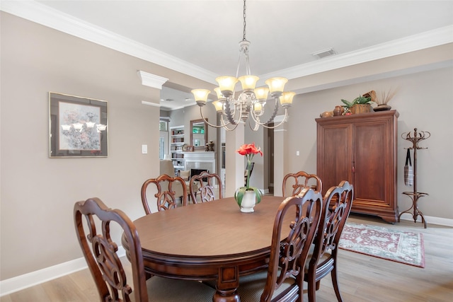 dining area featuring a fireplace, visible vents, baseboards, light wood finished floors, and crown molding