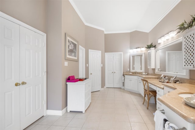 bathroom with crown molding, double vanity, a sink, tile patterned flooring, and baseboards