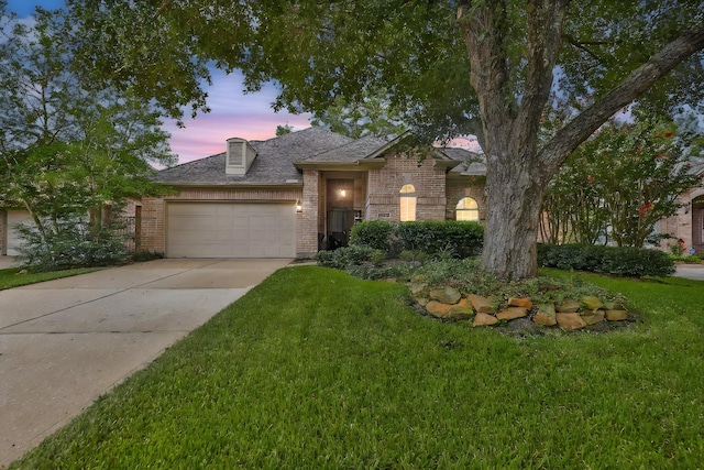 view of front of property with a garage, concrete driveway, brick siding, and a lawn