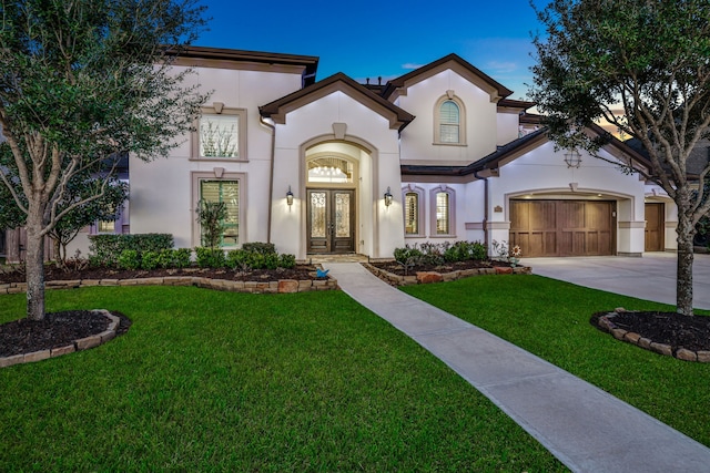 mediterranean / spanish-style home with driveway, french doors, a front lawn, and stucco siding