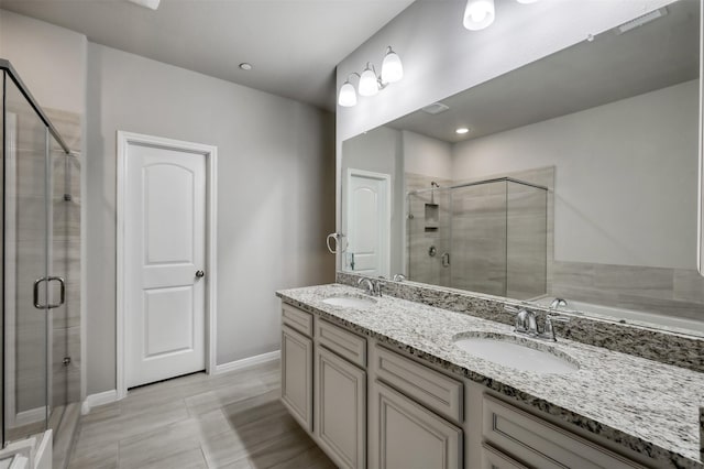 bathroom with double vanity, a stall shower, baseboards, and a sink