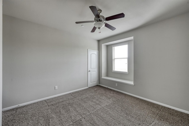 carpeted spare room featuring ceiling fan and baseboards