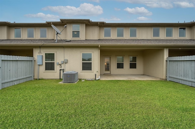 15331 Westland Gate Dr, Conroe, TX 77384 - back of property featuring a fenced backyard, a lawn, a patio area, a shingled roof, and central AC unit