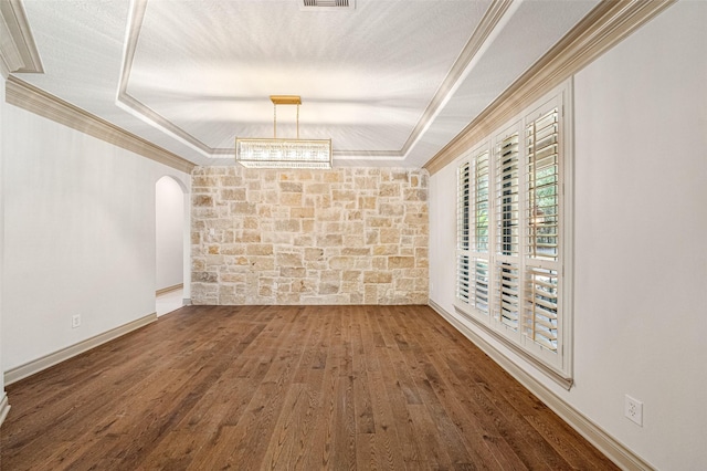 unfurnished room featuring a tray ceiling, arched walkways, crown molding, and wood finished floors