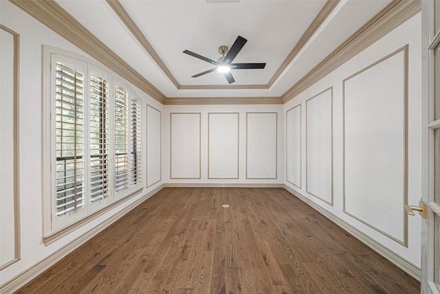 unfurnished room featuring ceiling fan, a decorative wall, wood finished floors, ornamental molding, and a tray ceiling