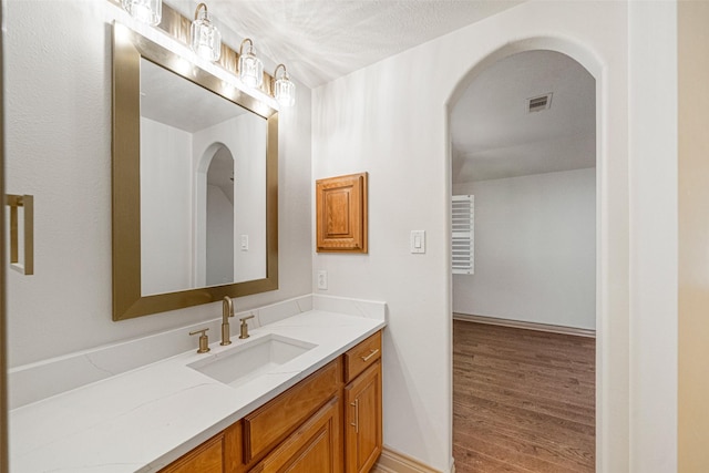 bathroom with visible vents, vanity, a textured ceiling, and wood finished floors