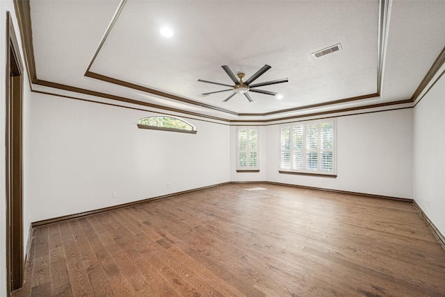 unfurnished room featuring a ceiling fan, visible vents, a raised ceiling, and wood finished floors