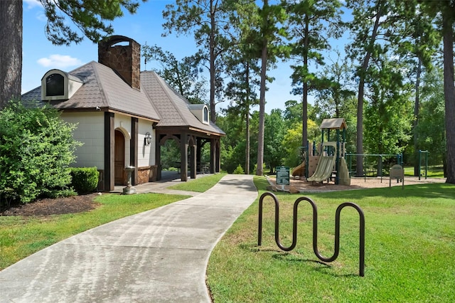 view of home's community featuring playground community and a lawn