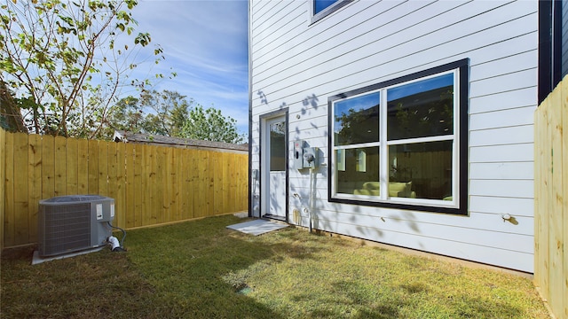 view of home's exterior with fence, central AC unit, and a yard