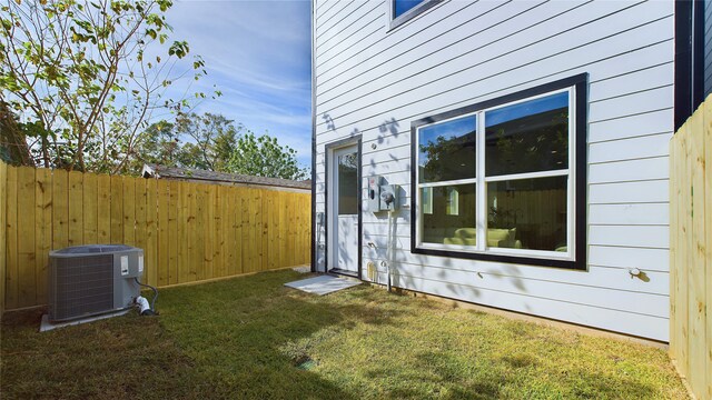 view of side of home with a lawn, central AC, and fence