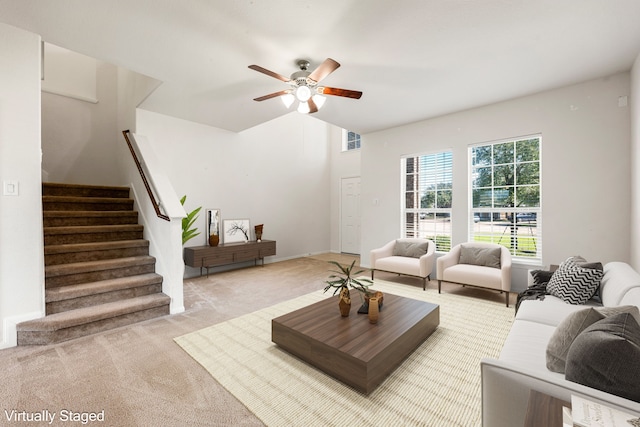 living area featuring light colored carpet, ceiling fan, visible vents, and stairs