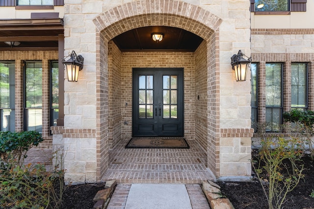 doorway to property featuring french doors, brick siding, and stone siding