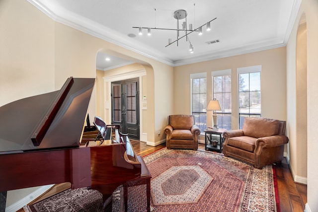 sitting room with visible vents, arched walkways, wood finished floors, and ornamental molding