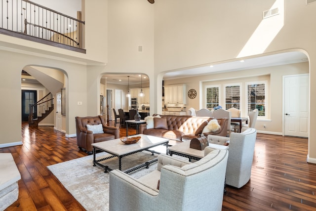 living room with arched walkways, visible vents, and hardwood / wood-style flooring