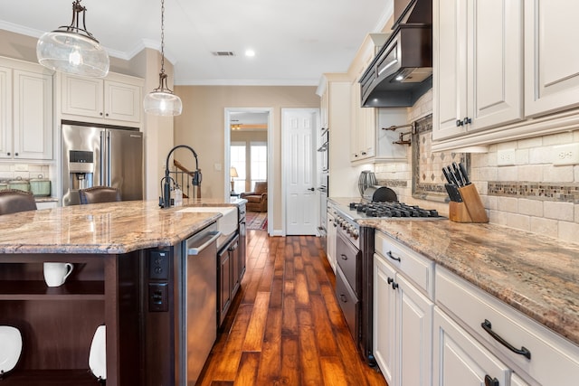 kitchen featuring crown molding, visible vents, appliances with stainless steel finishes, a sink, and premium range hood