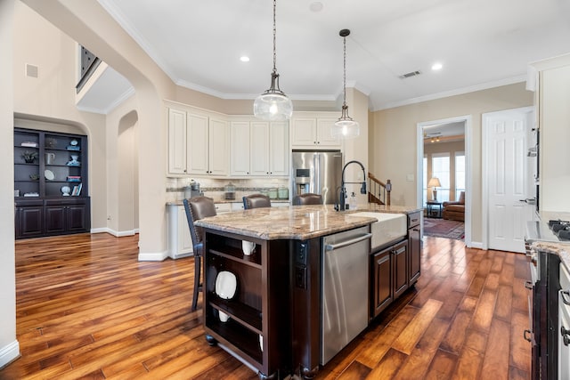 kitchen featuring visible vents, arched walkways, appliances with stainless steel finishes, open shelves, and a sink