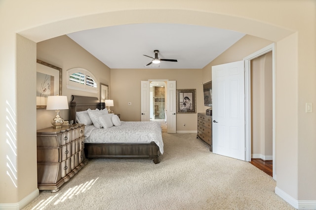 bedroom featuring arched walkways, light colored carpet, ceiling fan, ensuite bath, and baseboards