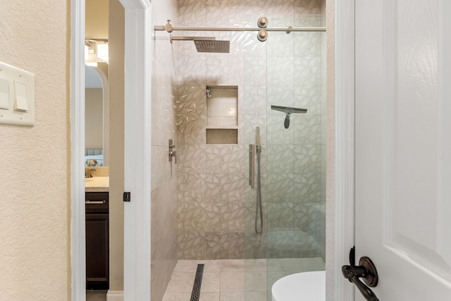 full bathroom with a textured wall, toilet, a shower stall, and vanity