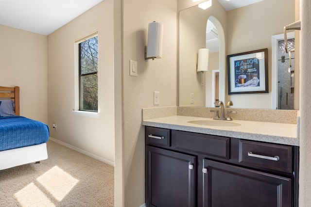 ensuite bathroom with ensuite bath, vanity, and baseboards