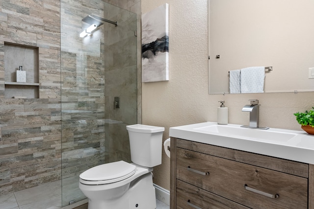 full bath featuring a tile shower, vanity, and toilet