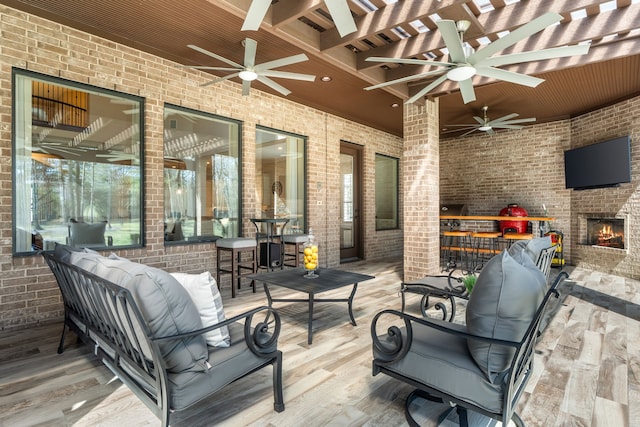 view of patio / terrace with ceiling fan and an outdoor living space with a fireplace