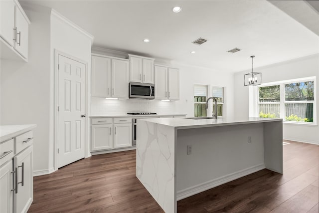 kitchen featuring dark wood-type flooring, a sink, visible vents, backsplash, and stainless steel microwave