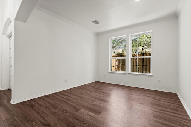 spare room with dark wood-style floors, visible vents, crown molding, and baseboards