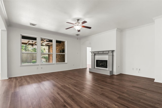 unfurnished living room with crown molding, visible vents, a fireplace with raised hearth, a ceiling fan, and dark wood-type flooring