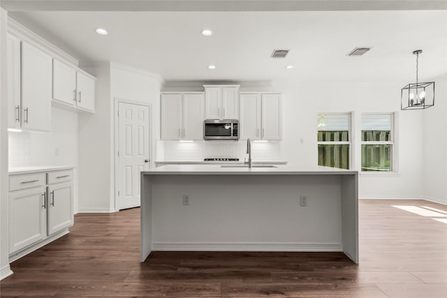 kitchen with dark wood-style floors, stainless steel microwave, a sink, and visible vents